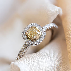 Cushion cut yellow diamond ring with a diamond halo and diamond shoulders