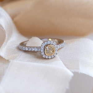 Cushion cut yellow diamond ring with a diamond halo and diamond shoulders