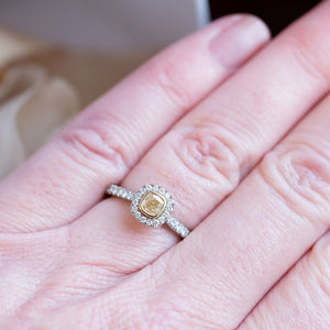 Cushion cut yellow diamond ring shown on hand