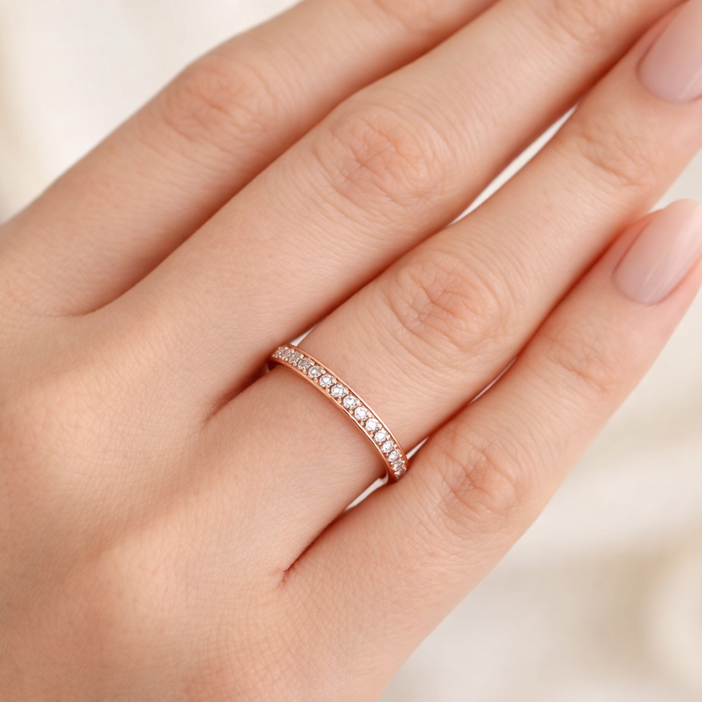 Rose gold ring with small diamonds on a hand against a light background