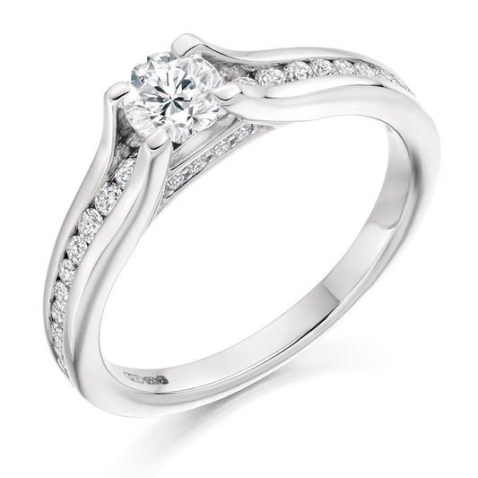 This Solitaire Engagement Ring has a 0.33ct Round Brilliant Cut centre diamond in a four claw setting.  It is beautifully accented by round brilliant cut diamonds both on the band and subtly under the main stone totalling 0.30ct  This gives total diamond weight of 0.63ct