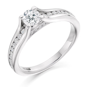 This Solitaire Engagement Ring has a 0.33ct Round Brilliant Cut centre diamond in a four claw setting.  It is beautifully accented by round brilliant cut diamonds both on the band and subtly under the main stone totalling 0.30ct  This gives total diamond weight of 0.63ct